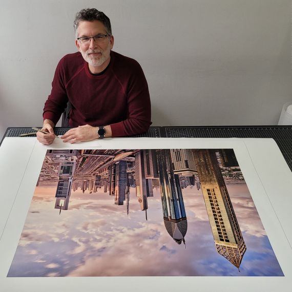Photographer Andrew Prokos signing a large-format limited edition photograph of the Dubai Cityscape for a photography exhibition.