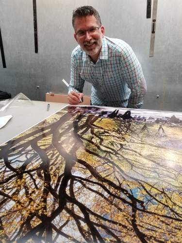 Photographer Andrew Prokos signing a 60" limited edition print of Poet's Walk in Autumn