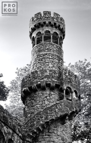 A black and white photo of the tower of the Poco Iniciatico, a hidden well with arched spiral stairway in the Quinta da Regaleira gardens of Sintra, Portugal