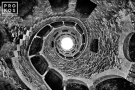 A black and white view of the Poco Iniciatico, a hidden well with arched spiral stairway in the Quinta da Regaleira gardens of Sintra, Portugal