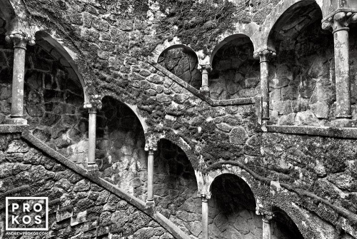 The Poco Iniciatico, a hidden well with arched spiral stairway in the Quinta da Regaleira gardens of Sintra, Portugal captured in black and white