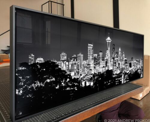 A large framed black and white photograph of the Seattle skyline at night by photographer Andrew Prokos