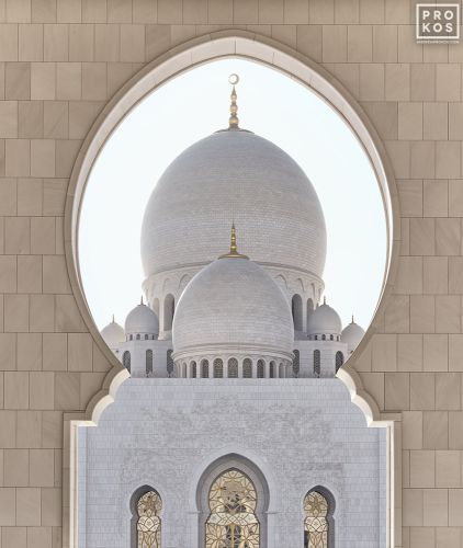 A fine art photo of the domes of Sheikh Zayed Grand Mosque framed by an Islamic arch, Abu Dhabi, UAE