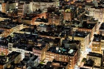 A long-exposure panoramic cityscape photo of the rooftops of SoHo New York City as seen from above at night.