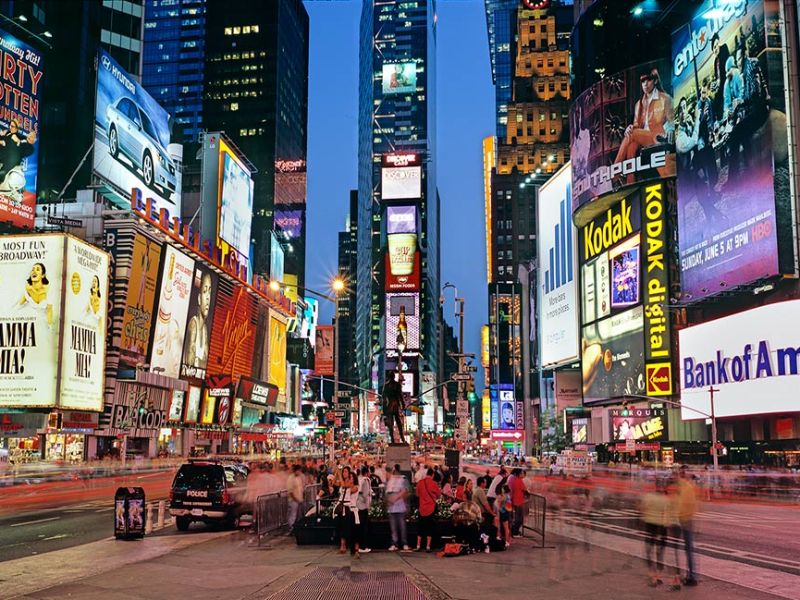 A panoramic cityscape photo of the signs of Times Square at dusk, New York City
