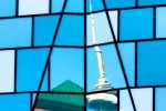 An architectural photo of CN Tower reflected on the glass facade of a Fashion District building, Toronto, Canada
