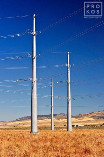 A landscape photo of a group of steel electricity transmission towers set in a sparse Southern Idaho landscape