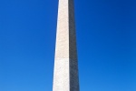 A view of the Washington Monument on a blue-sky summer day ringed with American flags, Washington DC. Fine art prints of this photo are available framed in wood, metal, and acrylic styles. 