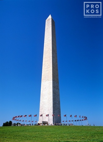 A view of the Washington Monument on a blue-sky summer day ringed with American flags, Washington DC. Fine art prints of this photo are available framed in wood, metal, and acrylic styles. 
